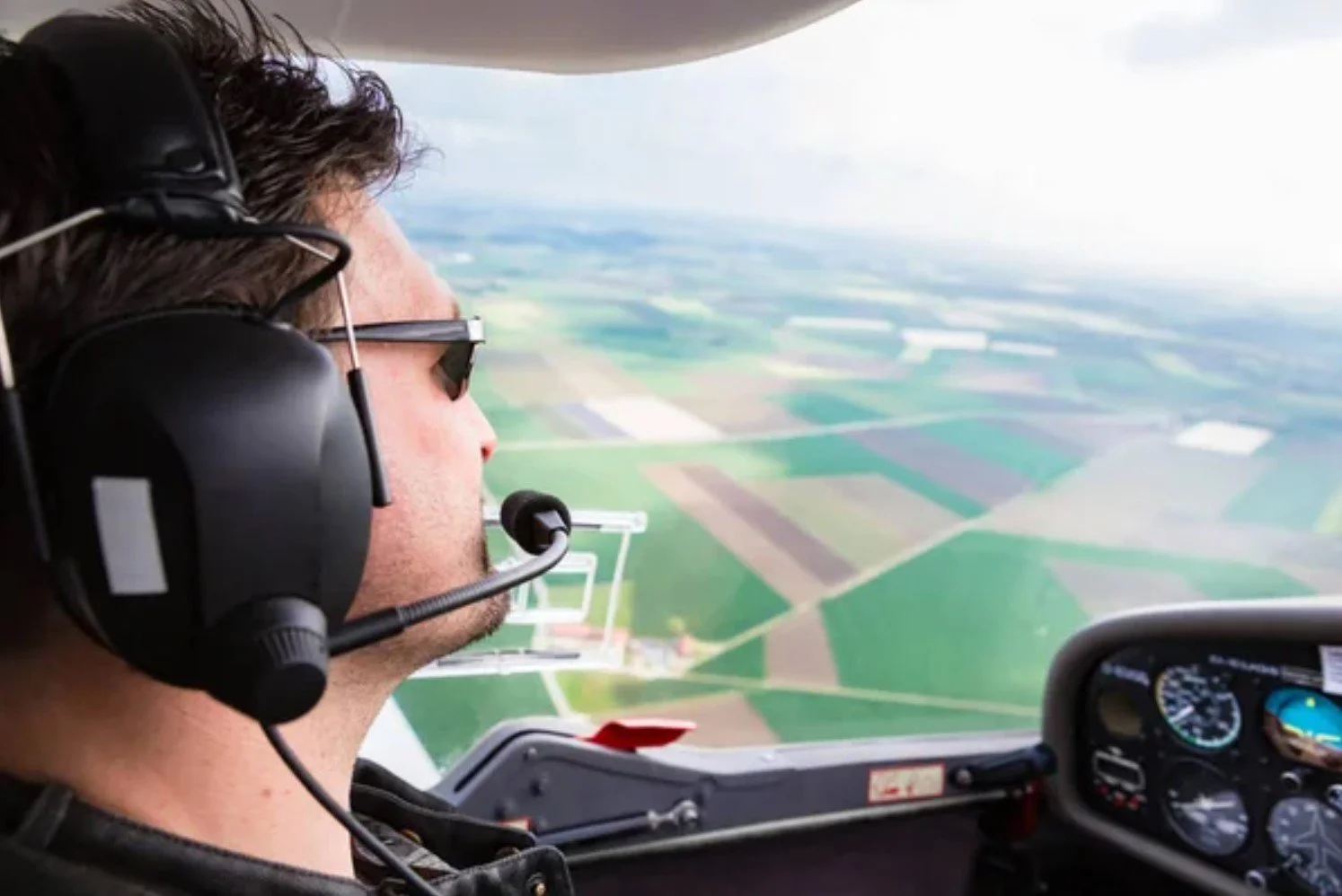 Pilot wearing a headset flying over farmland